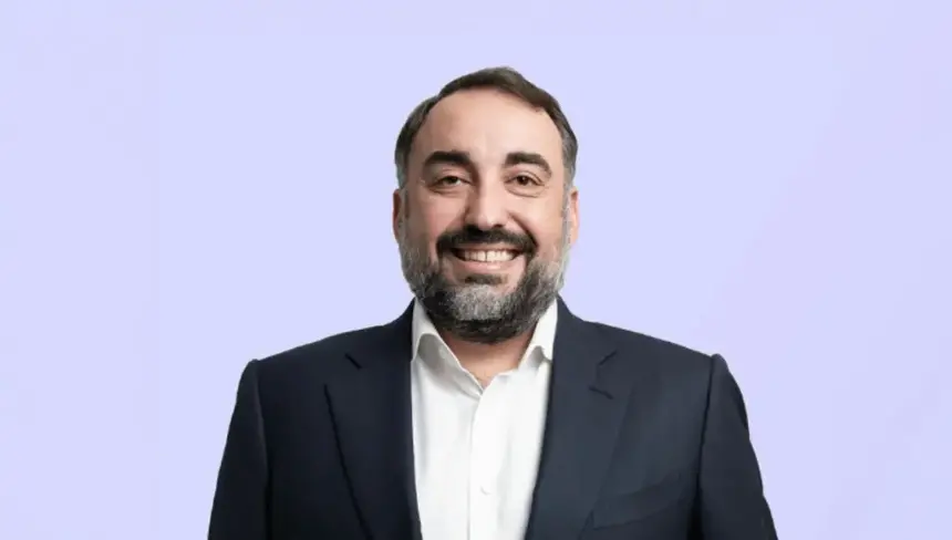 Security executive portrait of a man with a beard in a suit and smiling against a light background.