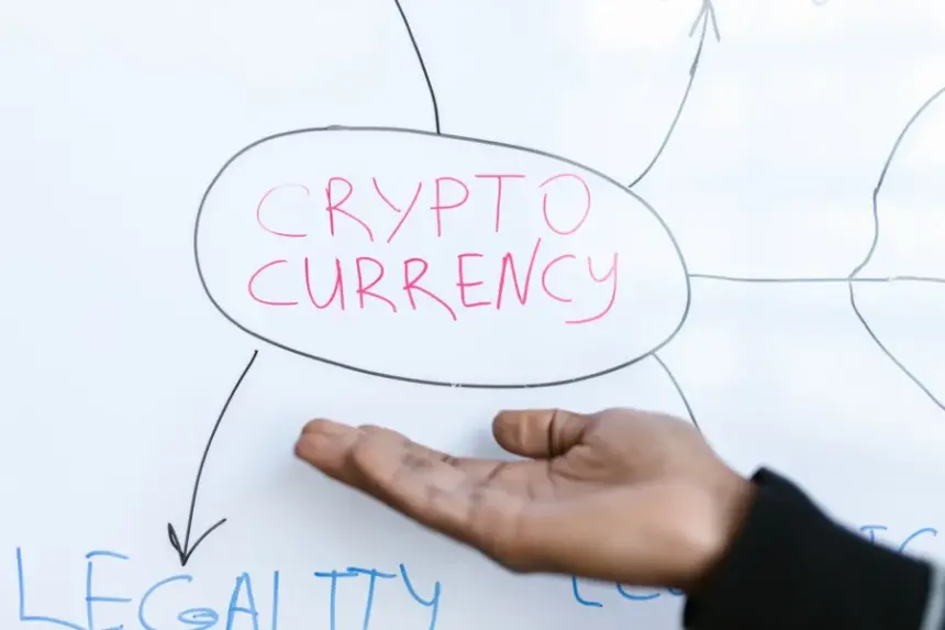 A person's hand gesturing towards a whiteboard diagram with the words CRYPTO CURRENCY and LEGALITY